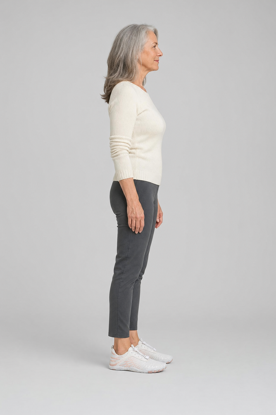A woman standing in the Cascade shoes, side view showing her hips, knees, ankles and the ball of her foot