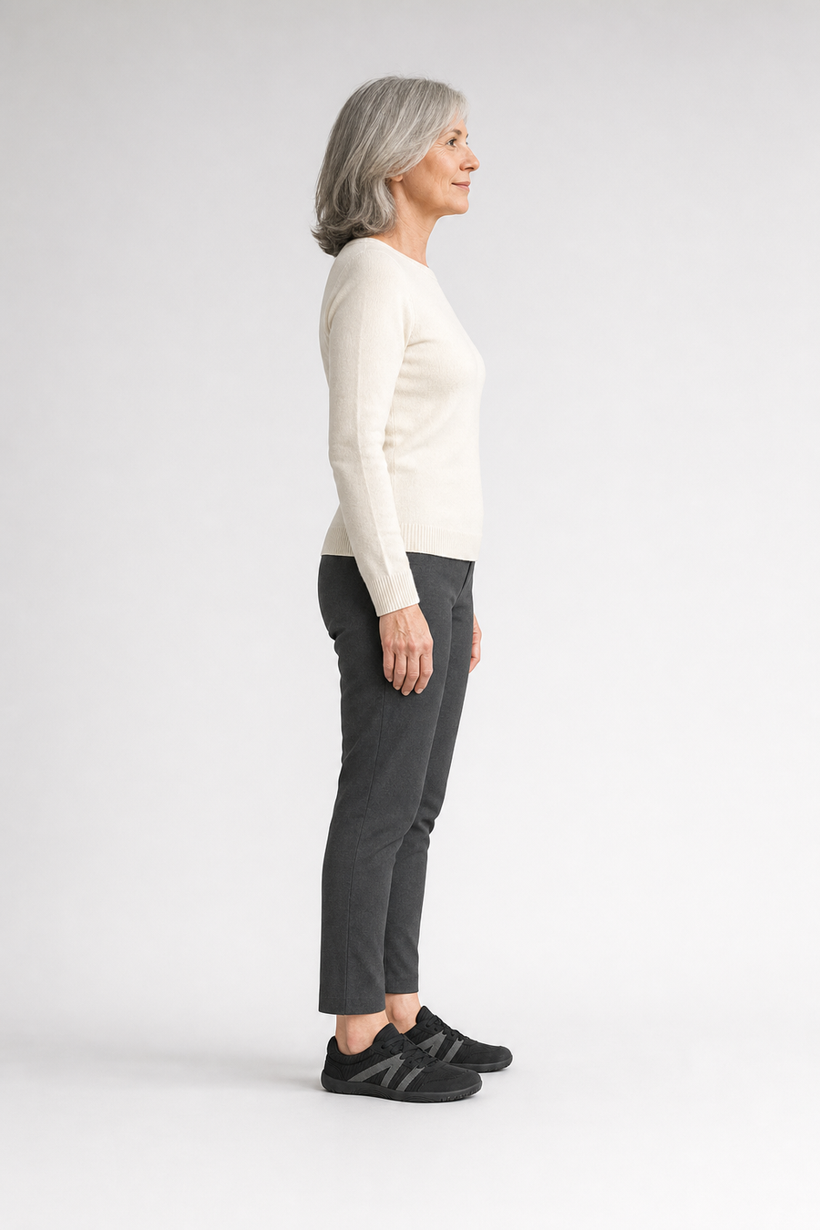 A woman standing in the Vale shoes, side view showing her hips, knees, ankles and the ball of her foot