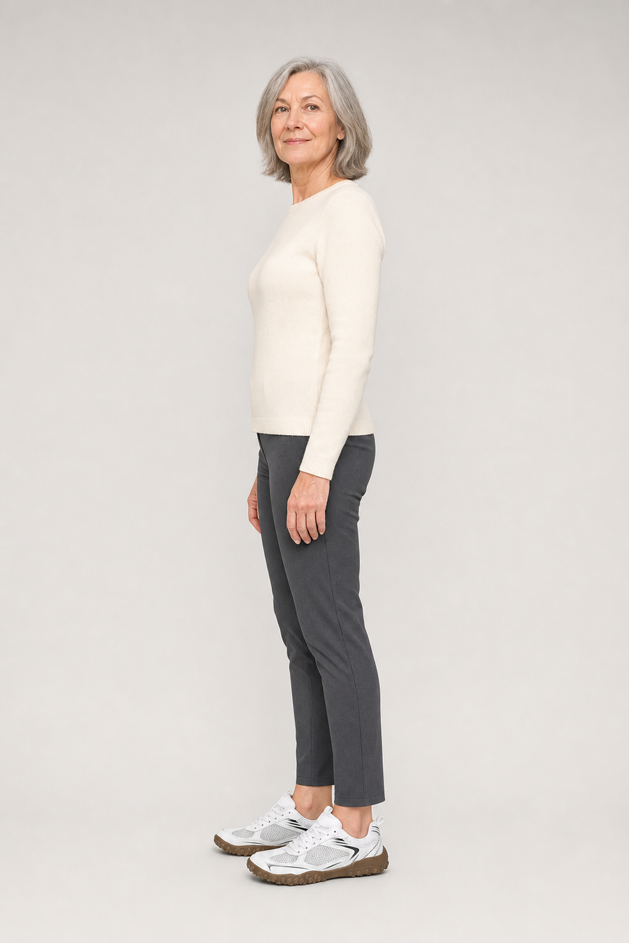 A woman standing in the Volt shoes, side view showing her hips, knees, ankles and the ball of her foot