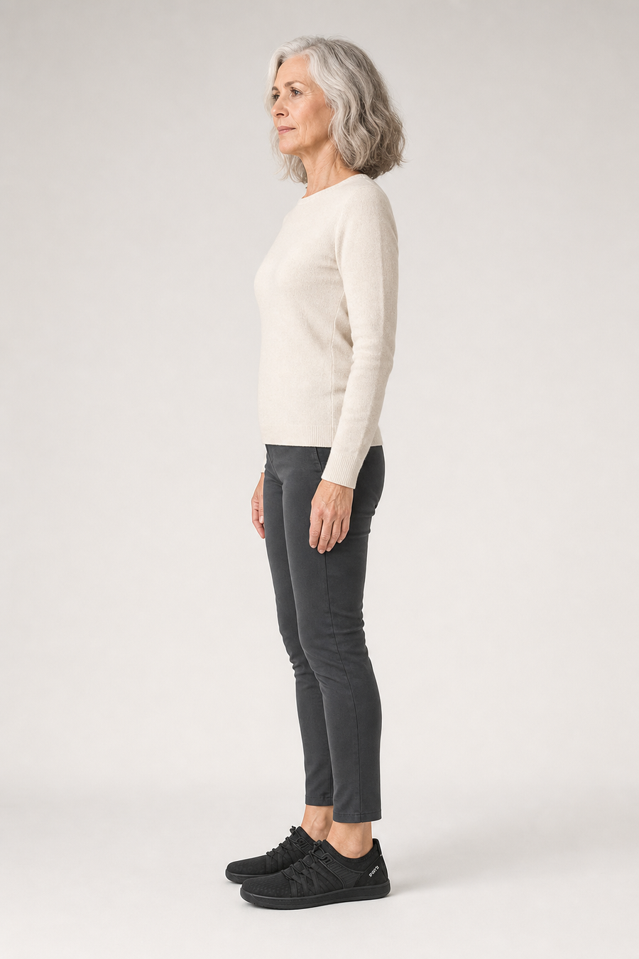 A woman standing in the Wave shoes, side view showing her hips, knees, ankles and the ball of her foot